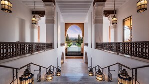 Una imponente escalera con barandillas ornamentadas y faroles, que conduce a una zona de piscina con vistas a montañas.