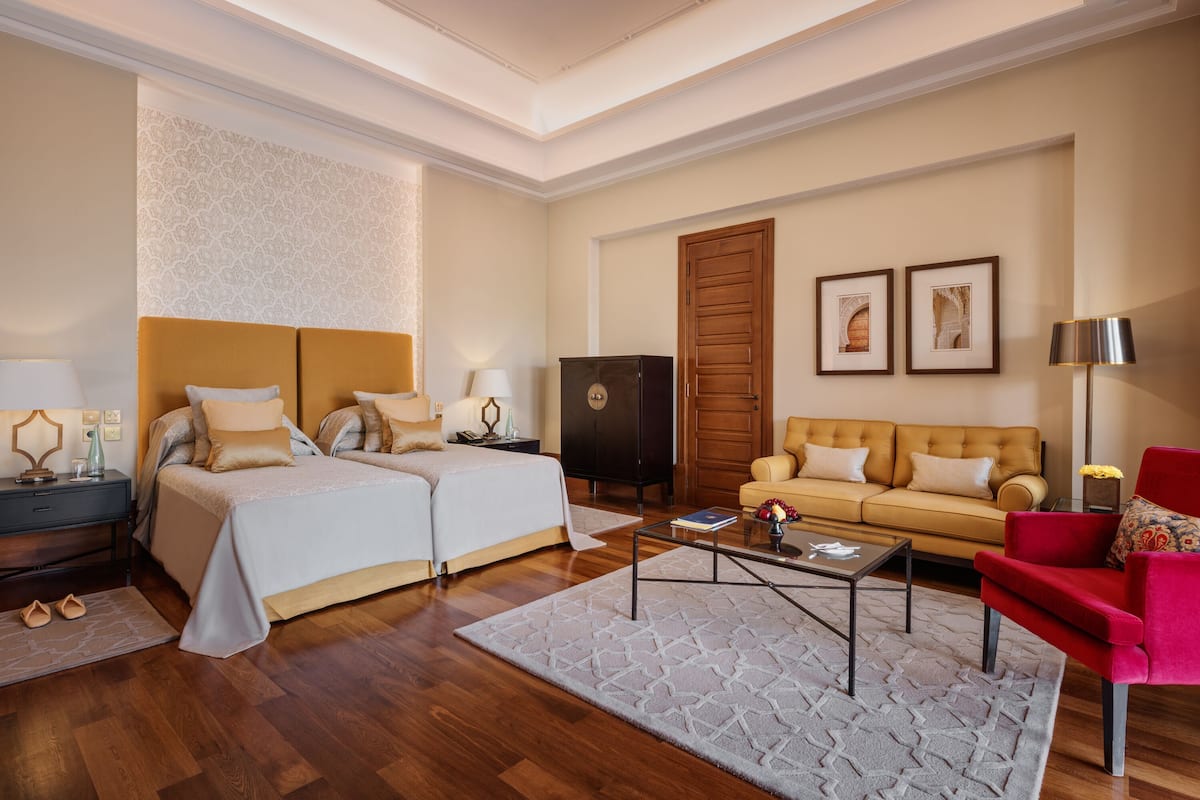 Ein Hotelzimmer mit einem Doppelbett, einem Sofa, einem Couchtisch und einem roten Sessel.