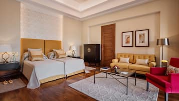 A hotel room with a double bed, a sofa, a coffee table, and a red armchair.