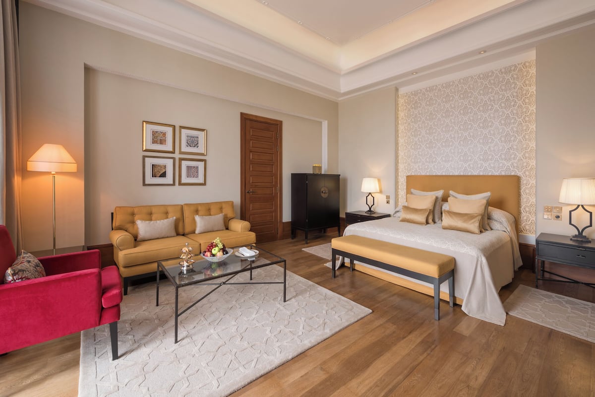 Ein Hotelzimmer mit Bett, einer Couch, einem roten Sessel, einem Couchtisch und einem Fernseher.