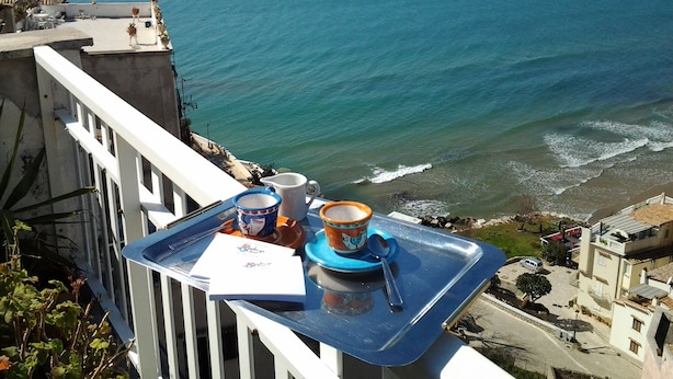 A balcony with a tray of items, overlooking a coastal view with the sea and distant mountains. - Casa Celeste Sperlongaresort (Sperlonga)