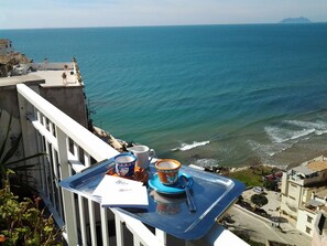 Ein Balkon mit einer Ablage, der Blick auf die Küste, das Meer und ferne Berge gewährt.