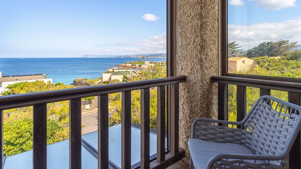 A balcony with a view of the sea and buildings.