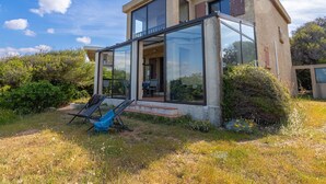 A modern house with a glass extension, outdoor seating, and a garden.
