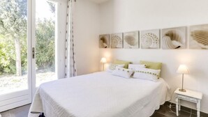 Een slaapkamer met een groot bed, een schuifpui naar een balkon en wanddecoratie.