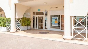 A building entrance with a glass door, a small outdoor seating area, and potted plants. - Le Cesarée by Interhome (Fréjus)