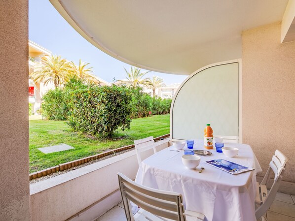 Een balkon met een tafel gedekt voor twee personen, een fles sinaasappelsap en een menukaart.