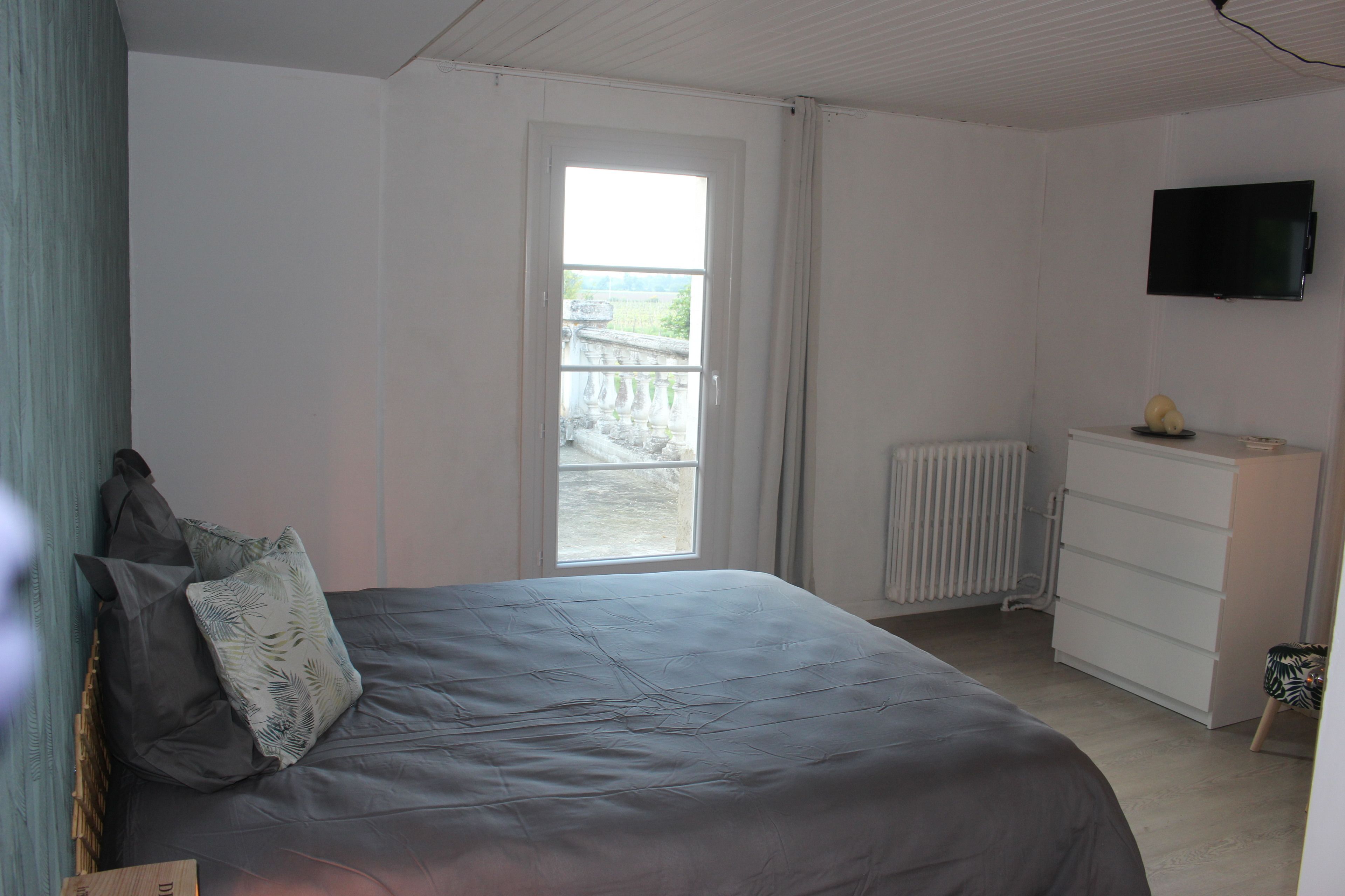 Une chambre à coucher avec un lit, une commode, un radiateur et un téléviseur fixé au mur.