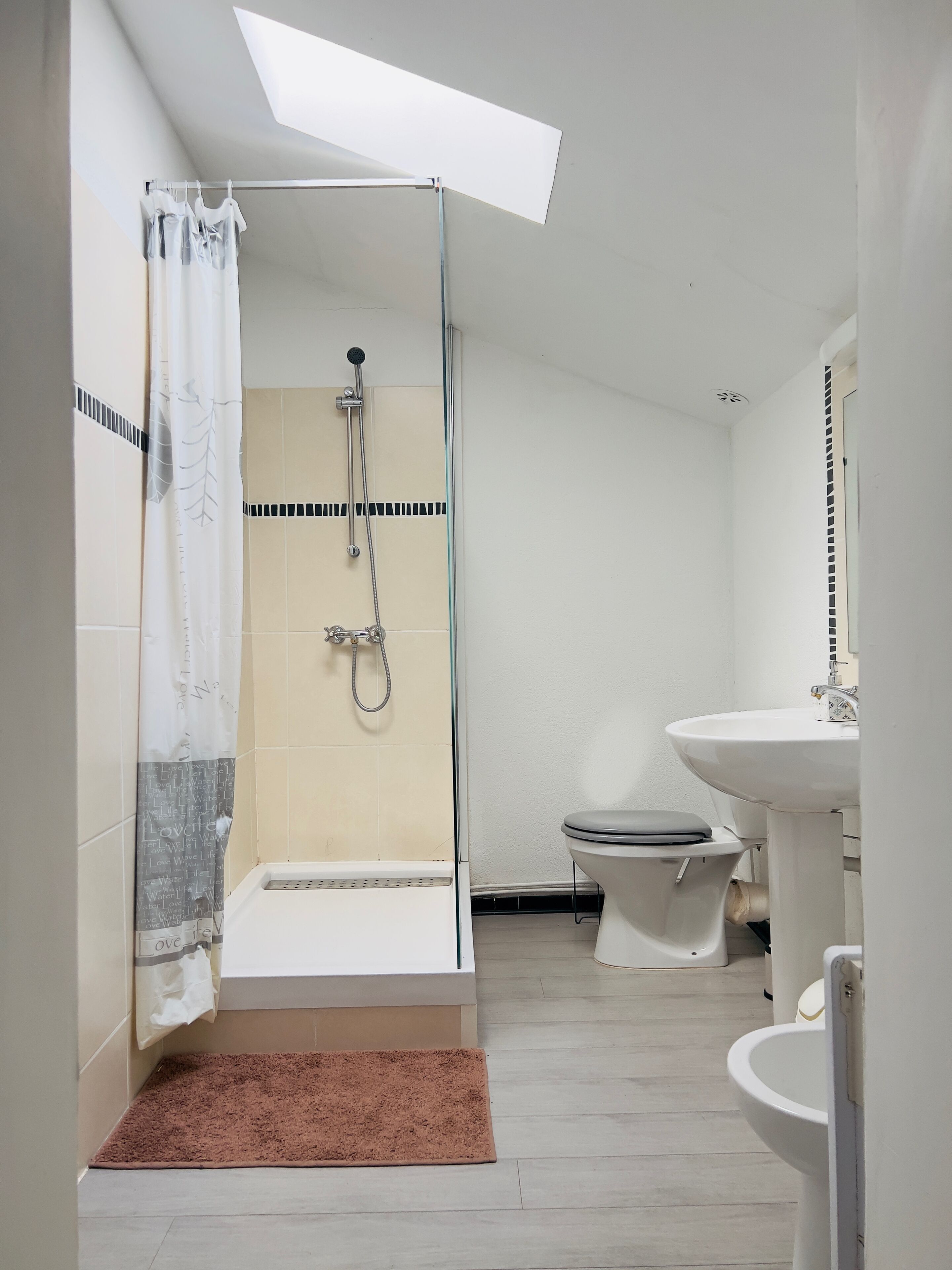 Un baño moderno con cabina de ducha de vidrio, inodoro y lavabo.