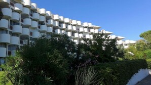 A modern hotel with a unique cylindrical balcony design, lush greenery in front, and a clear blue sky. - Cap Sud by Interhome (La Grande Motte)