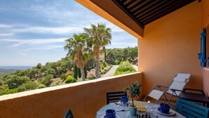 A balcony with a table set for two, overlooking a lush landscape with palm trees and a view of the sea. - Les Hauts des Issambres by Interhome (Les Issambres)