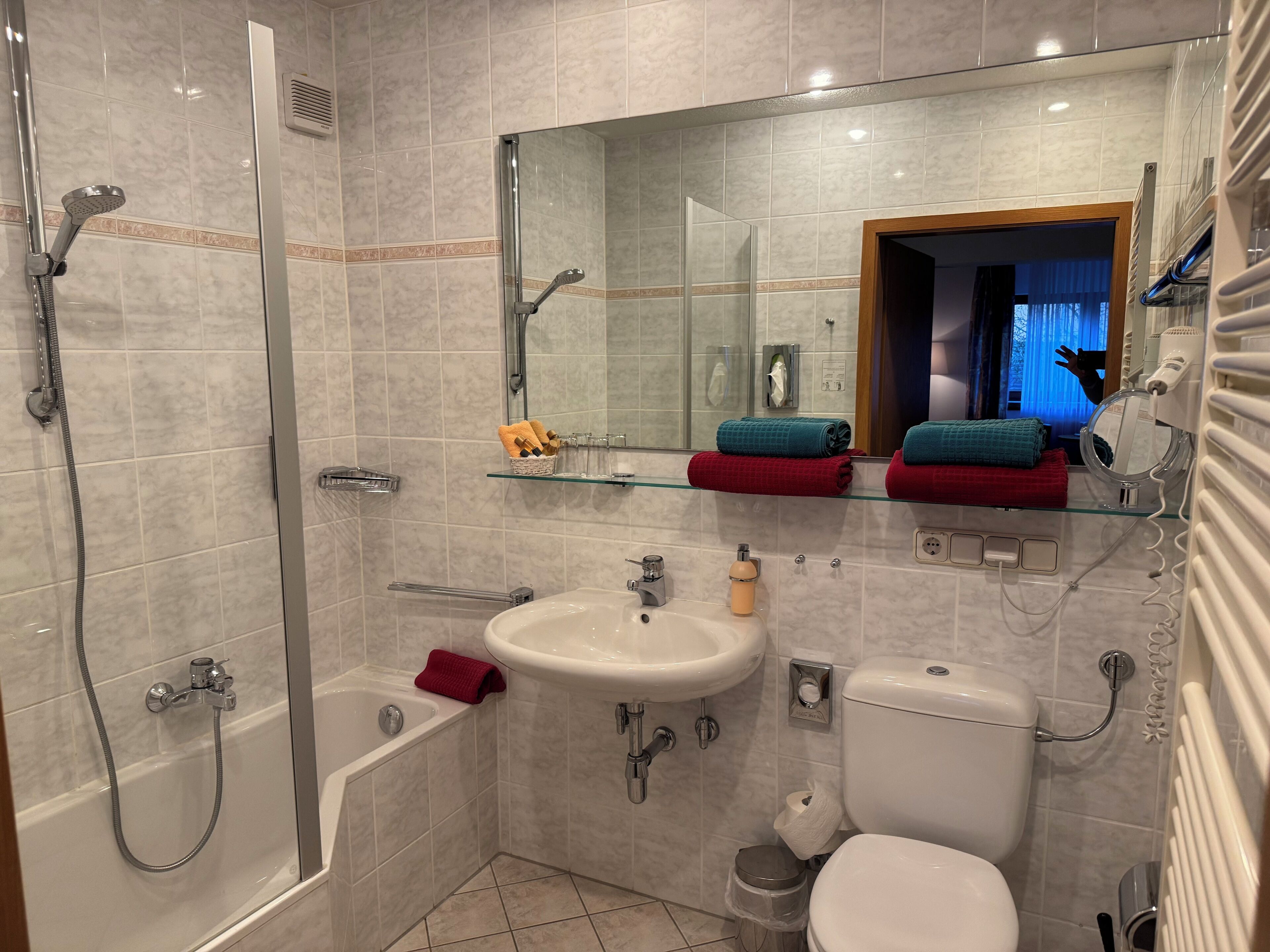 A modern bathroom with a glass shower enclosure, a bathtub, a sink, and a toilet.