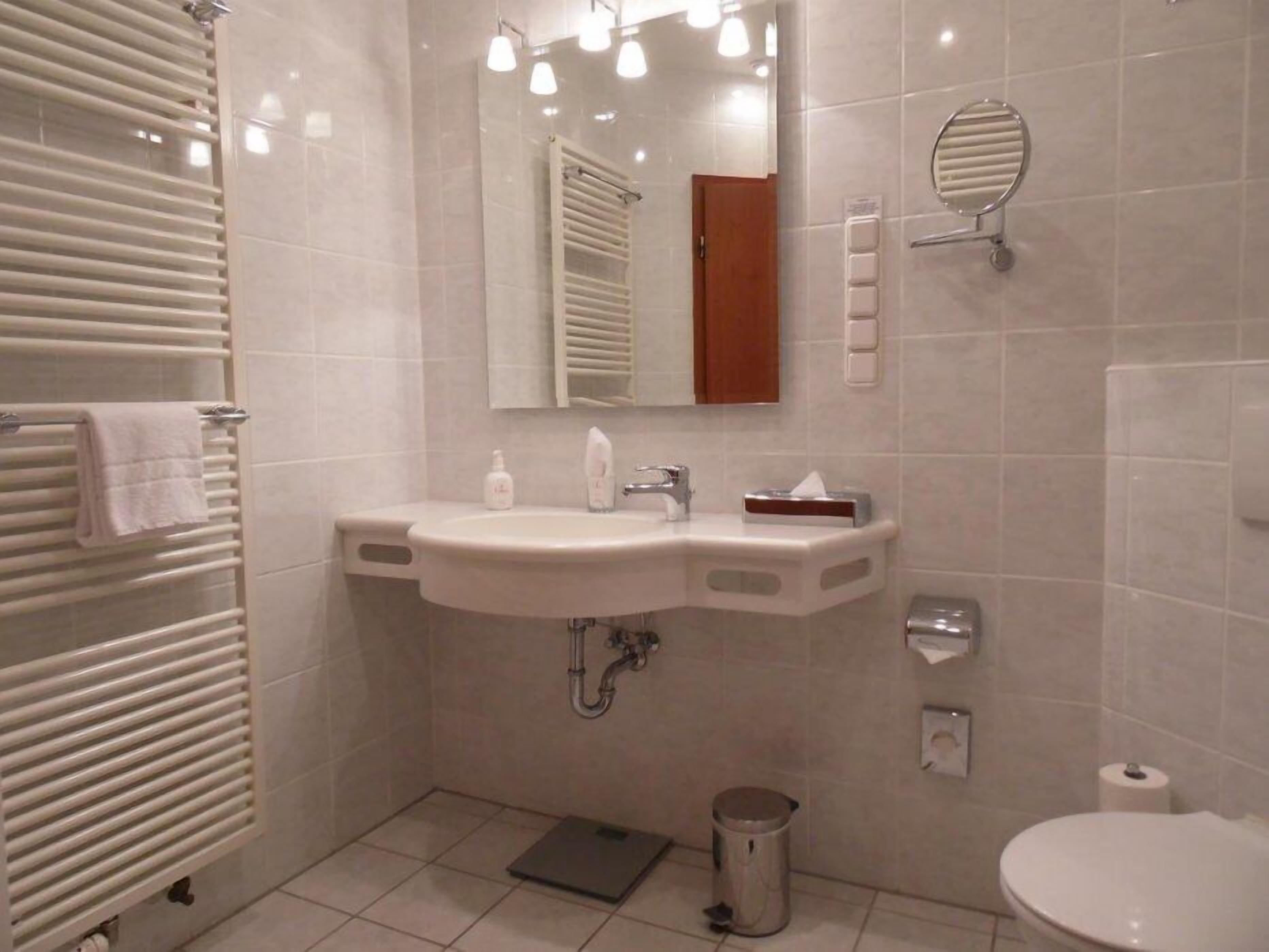 Un baño moderno con lavamanos, espejo y toallero blancos.