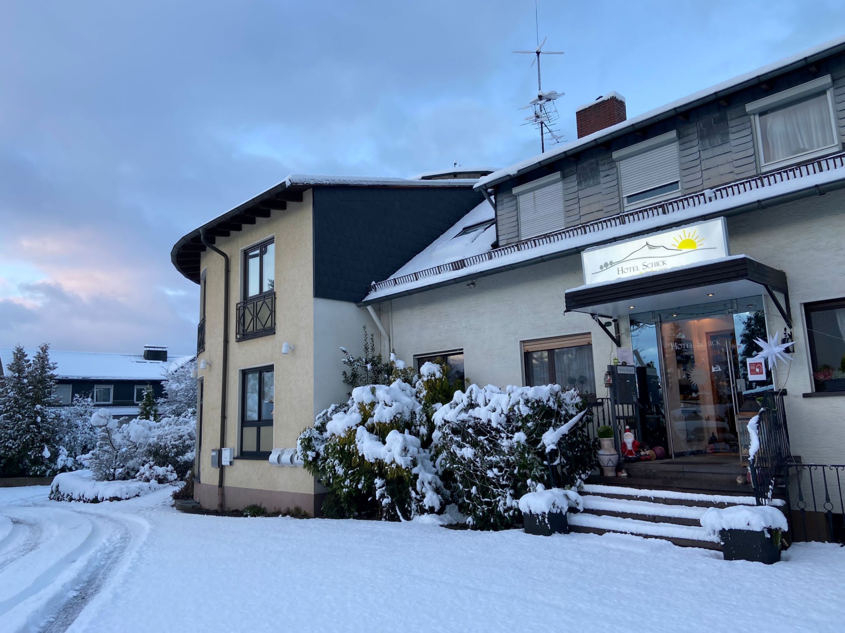 A hotel with a snow-covered entrance and a sign reading "Hotel Schick."