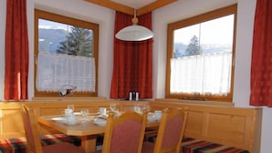 A dining area with a wooden table set for four, surrounded by chairs with red cushions, and a bench along the wall. - Herbert by Interhome (Kaltenbach)
