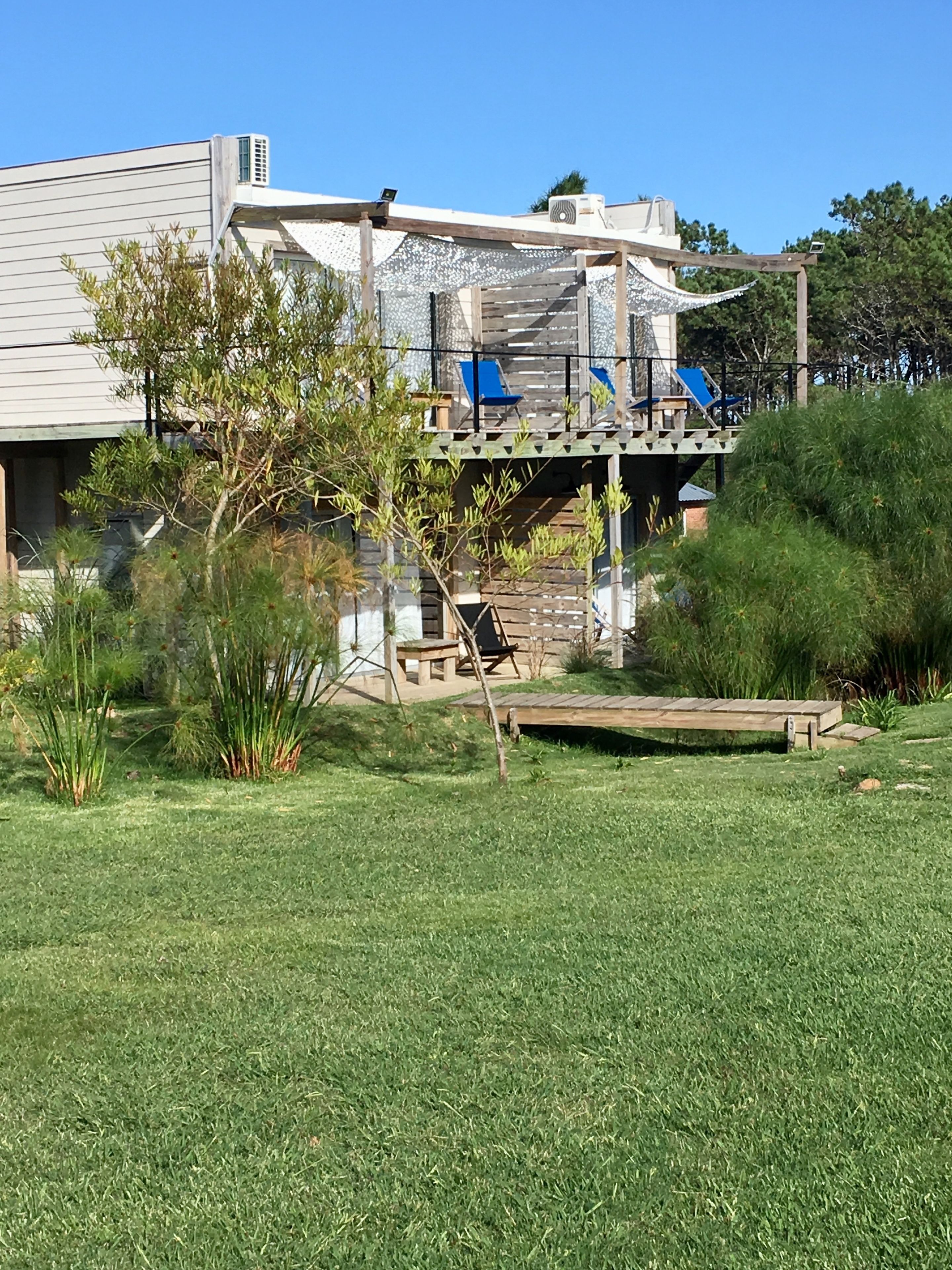 A modern house with a deck, a small garden, and a pond.