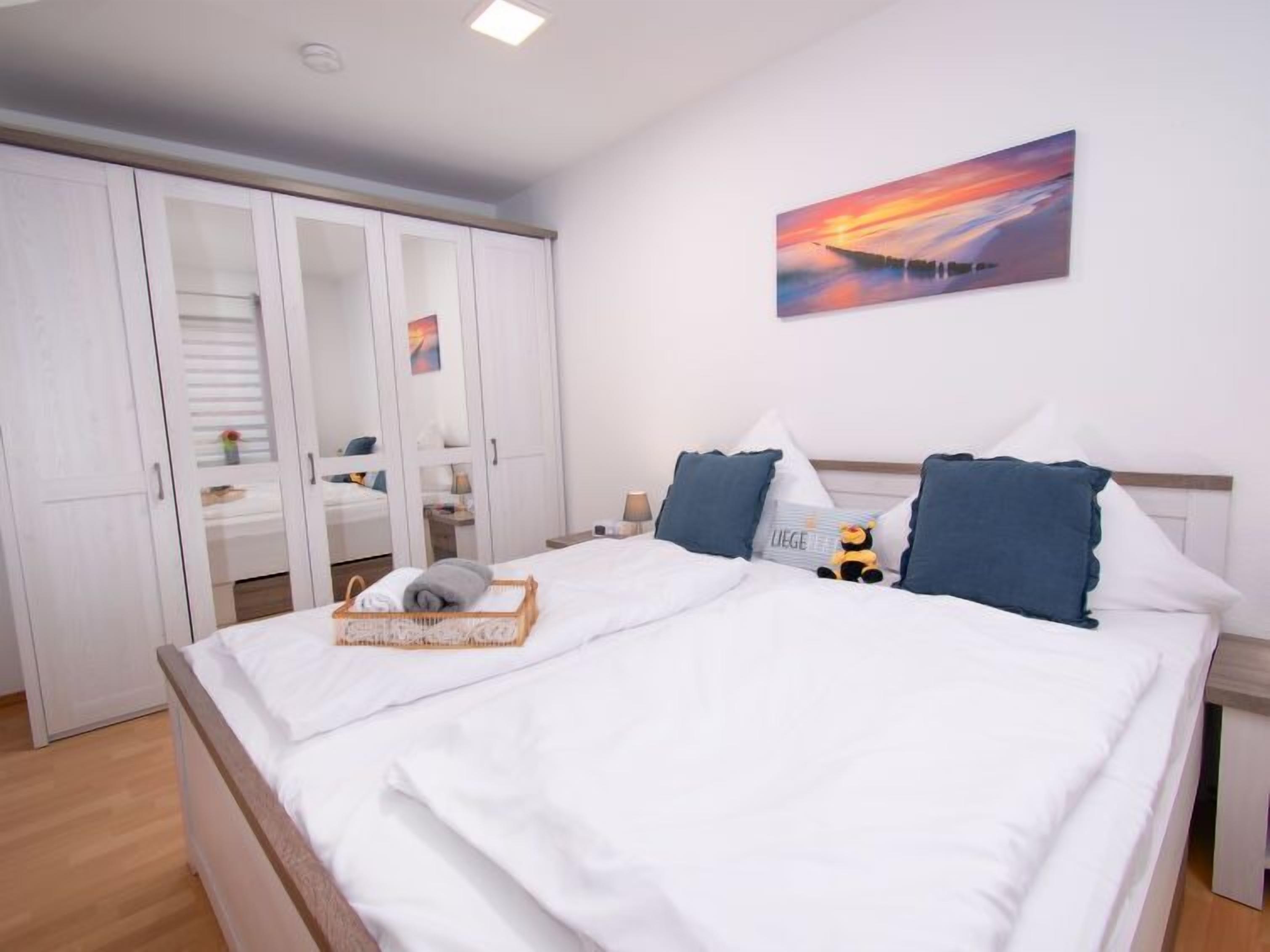 Quarto bem arrumado com uma cama grande, um guarda-roupa com portas de vidro e um quadro na parede.