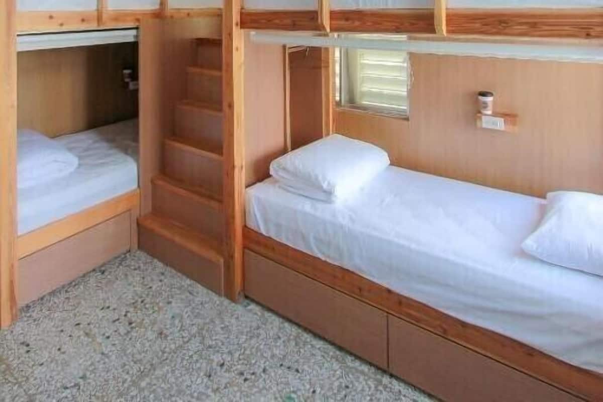 Dormitorio con literas de madera y ropa de cama blanca.