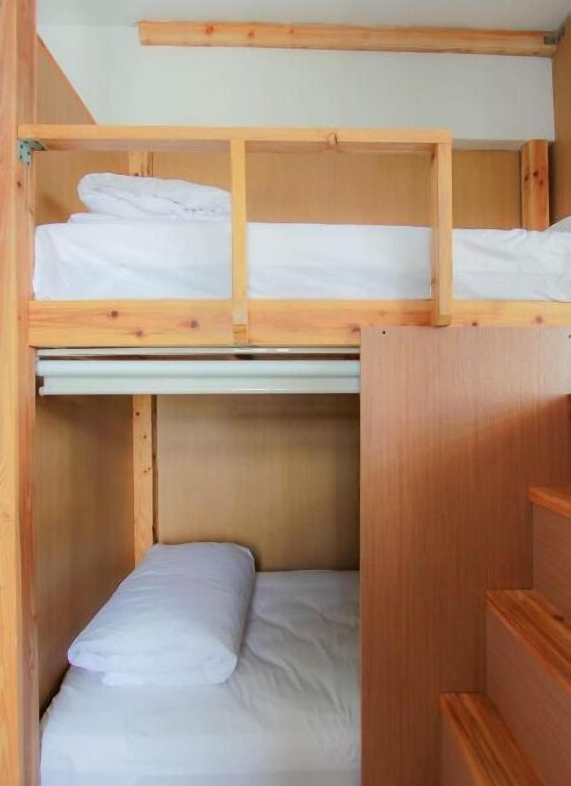 A bunk bed room with wooden frames and white bedding.
