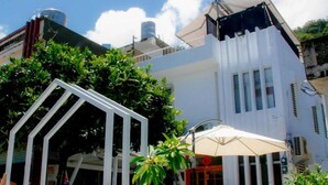 A modern building with a white facade, large windows, and a rooftop water tank. - Mayhow Donghe - Hostel (Donghe)