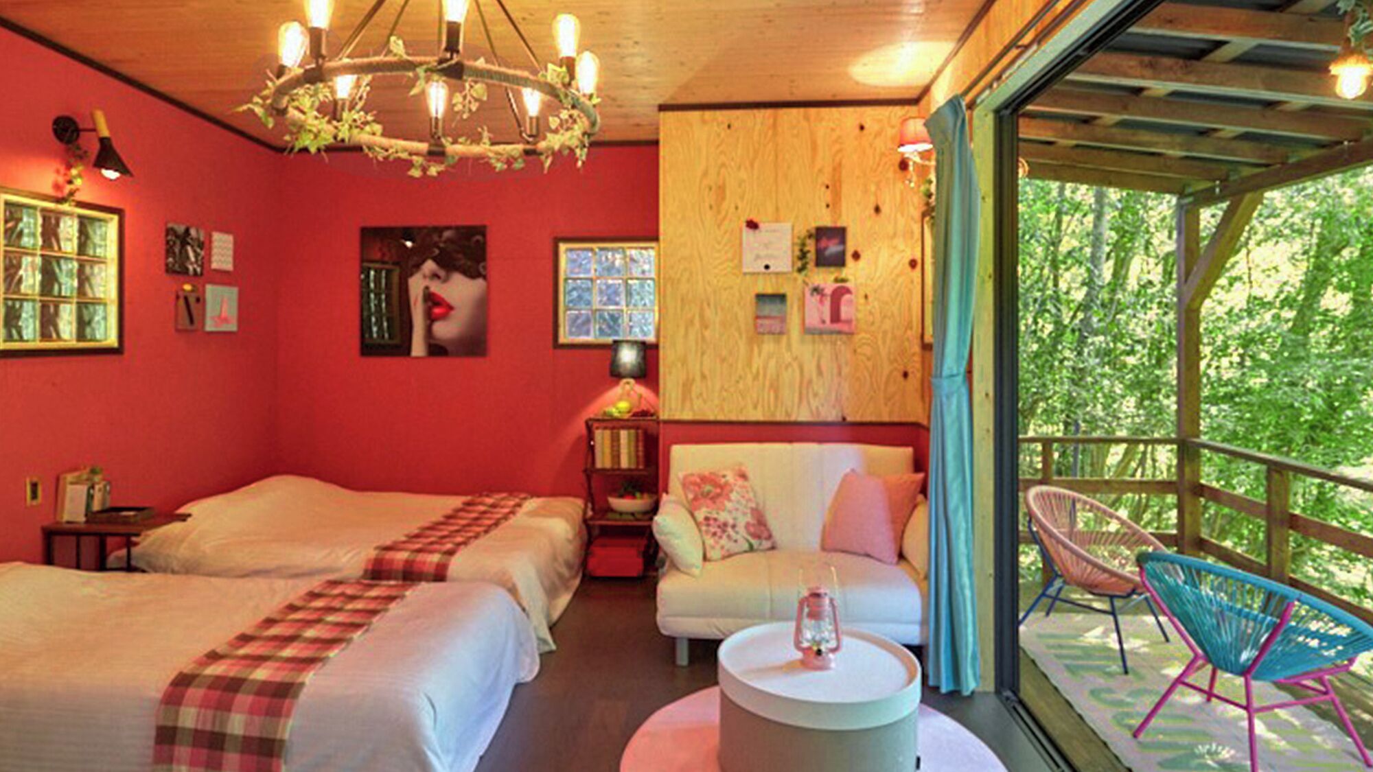 Una habitación con dos camas, una mesa redonda, una silla y un balcón con vistas a árboles.