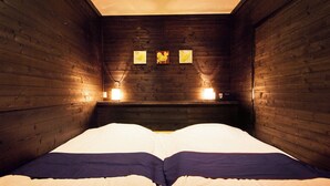 Una stanza in legno con un letto, due luci a parete e tre quadri appesi al muro.