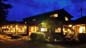 Un'abitazione tradizionale giapponese con facciata in legno, un portico con posti a sedere e un ingresso ben illuminato.