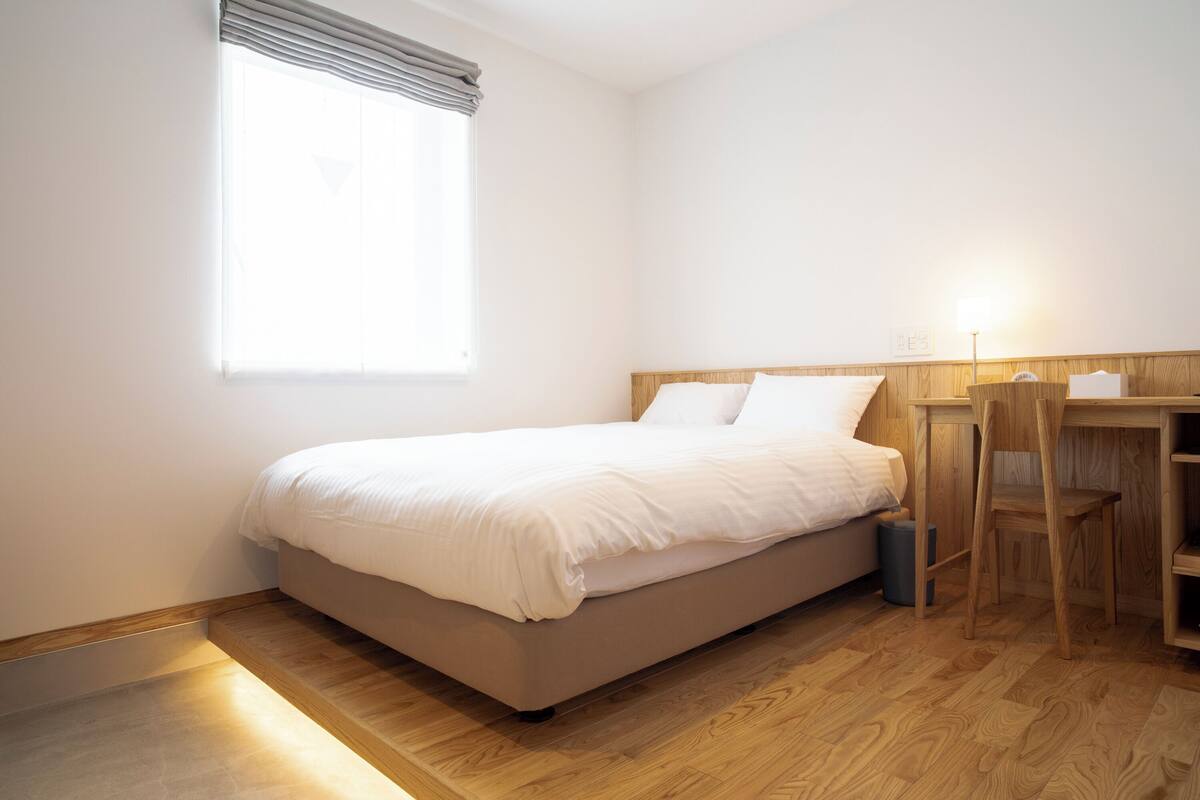 A bedroom with a bed, a desk, and a chair.