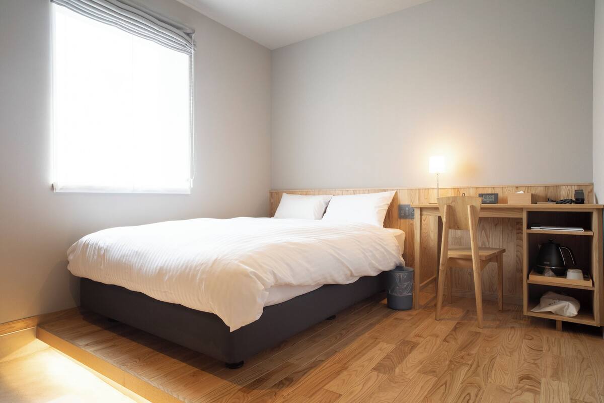 A bedroom with a bed, a desk, and a chair.