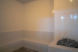 A bathroom with white tiled walls and a bench. - Mascos Hotel (Masuda)
