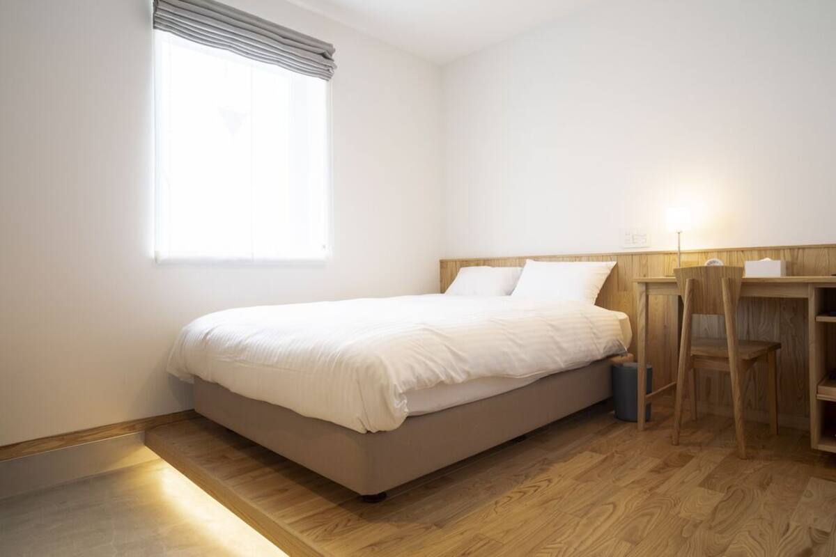 A bedroom with a bed, a desk, and a chair.
