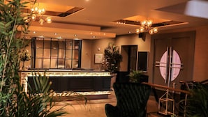 A modern interior with a bar area, a black upholstered chair, and multiple hanging light fixtures. - The Lansdowne Hotel (Belfast)