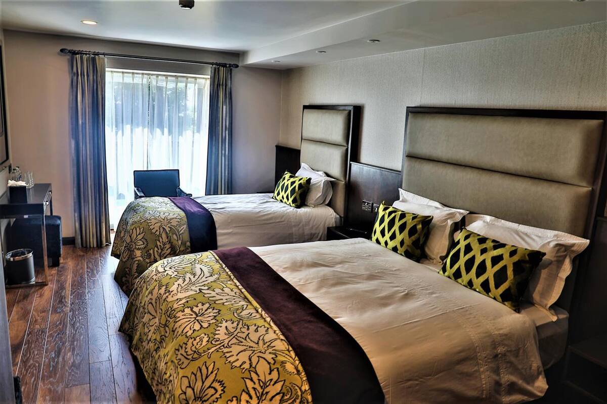 A hotel room with two beds, a desk, and a chair.