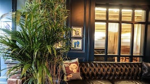 A room with a large potted plant, a leather sofa, and framed pictures on the wall. - The Lansdowne Hotel (Belfast)