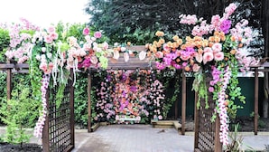 A wooden pergola with a floral archway, surrounded by a brick pathway and greenery. - The Lansdowne Hotel (Belfast)