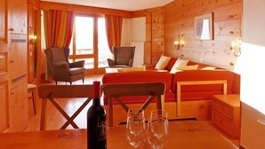 Une chaleureuse cabane en bois avec une table à manger, des chaises, une bouteille de vin et des verres.
