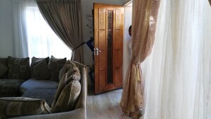 A room with a sofa, patterned cushions, a wooden door, and a curtain. - Lapeng Home Away from Home (Maseru)