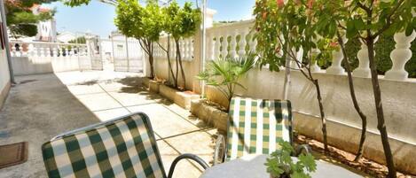 An outdoor patio with checkered chairs, a table, and potted plants.