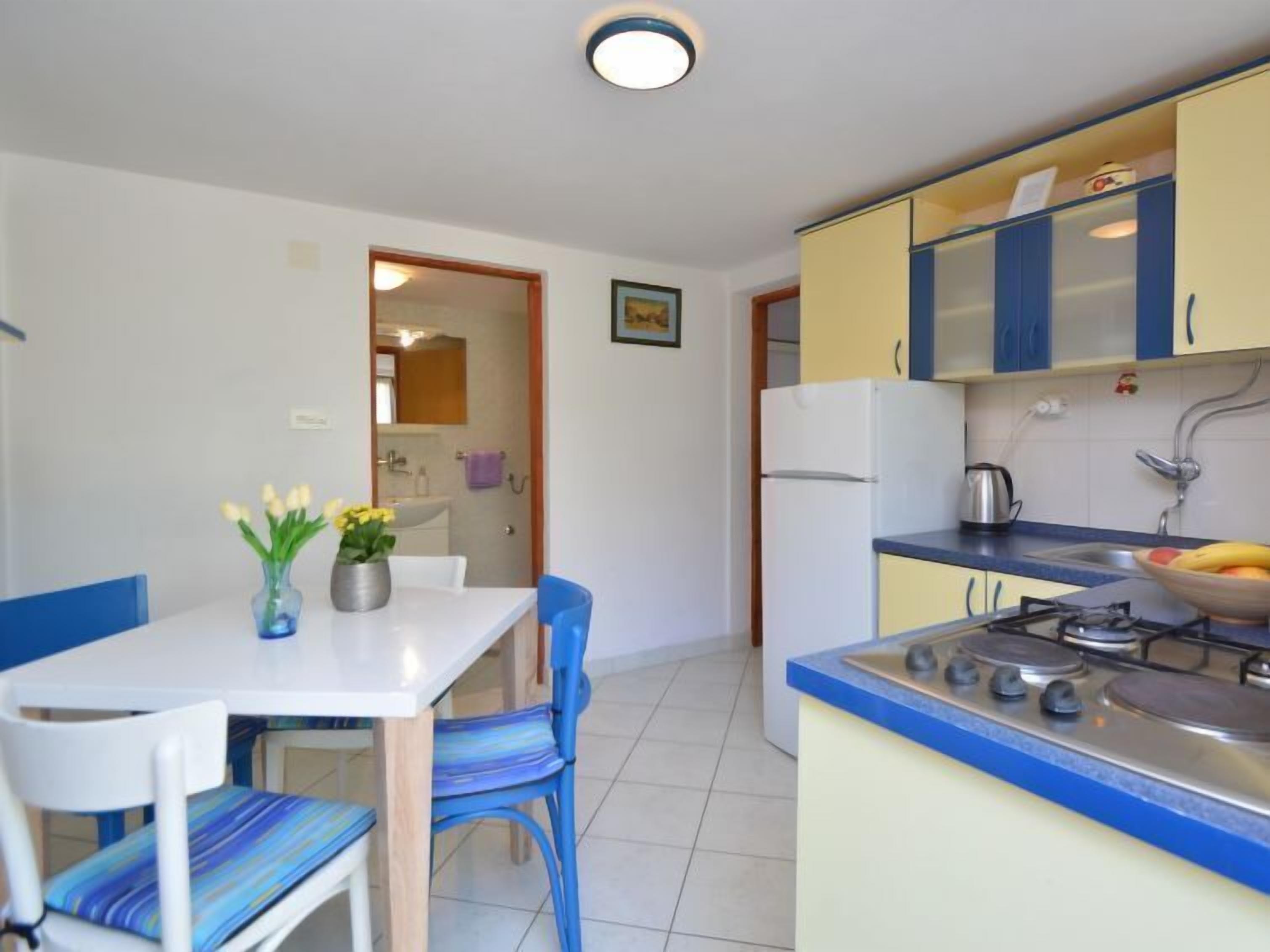 A compact kitchen with a dining area, featuring a table with chairs, a stove, and a sink.