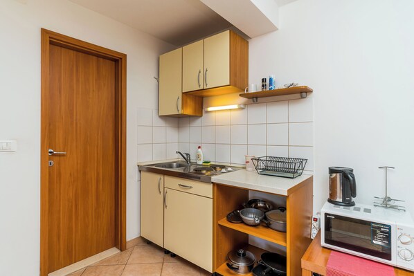 Cozinha compacta com armários de madeira, micro-ondas e cafeteira.