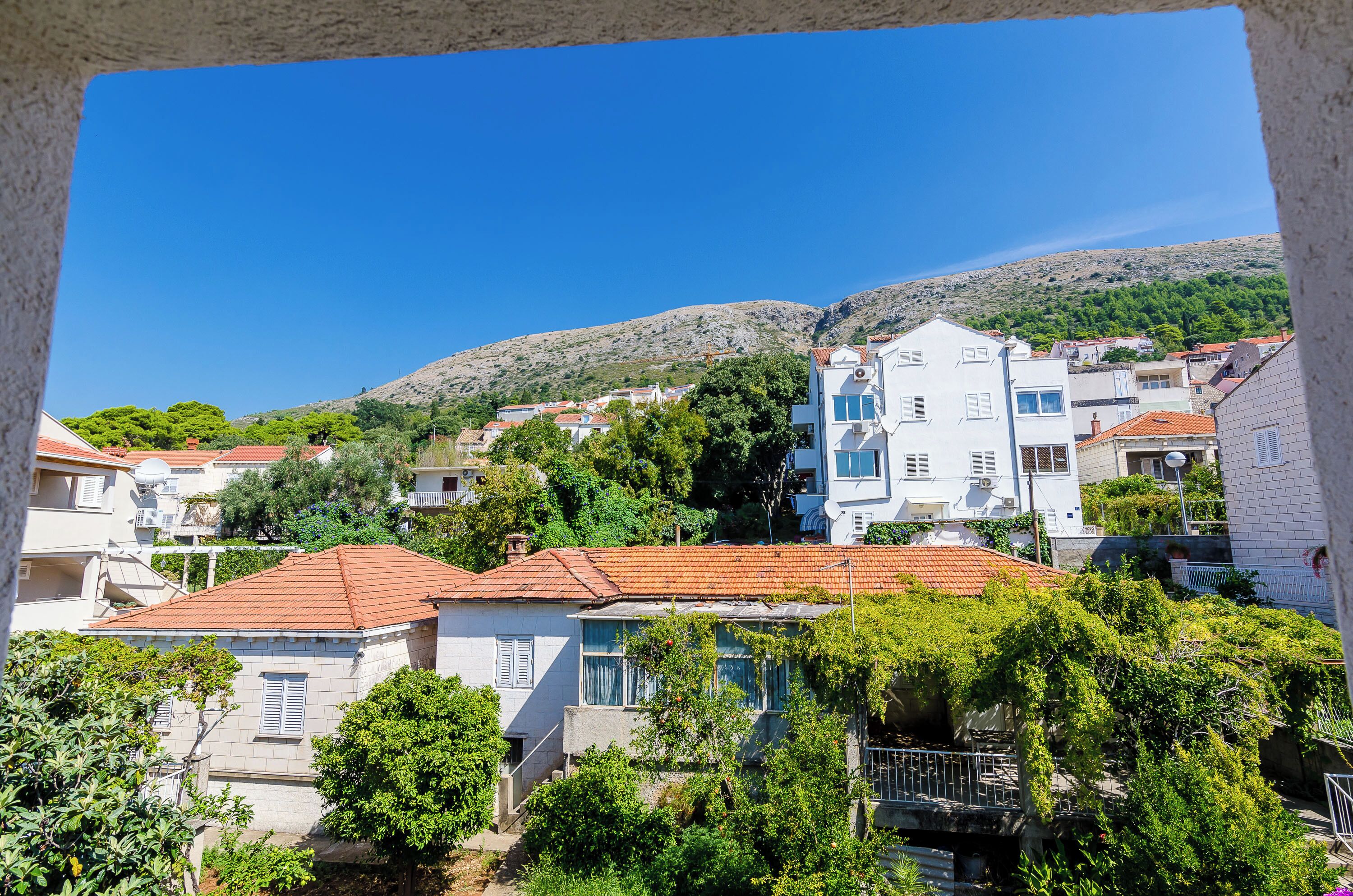 A residential area with houses, a hillside, and a clear blue sky.
