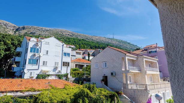 A hillside residential area with multi-story buildings, some with balconies, under a clear blue sky. - Apartmani Princ Hrvoje (Dubrovnik)