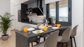 A modern kitchen with a dining area, a large window with a view, and a potted plant. - Villa Four Brothers Penthouse Suite (Podstrana)