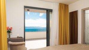 A hotel room with a bed, a desk, a chair, and a view of the sea through an open door. - Villa Four Brothers Penthouse Suite (Podstrana)