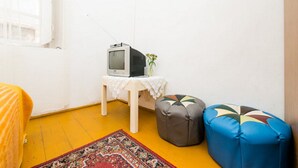 A room with a television on a small table, a patterned rug, and two bean bag chairs. - Rooms Kisic (Dubrovnik)
