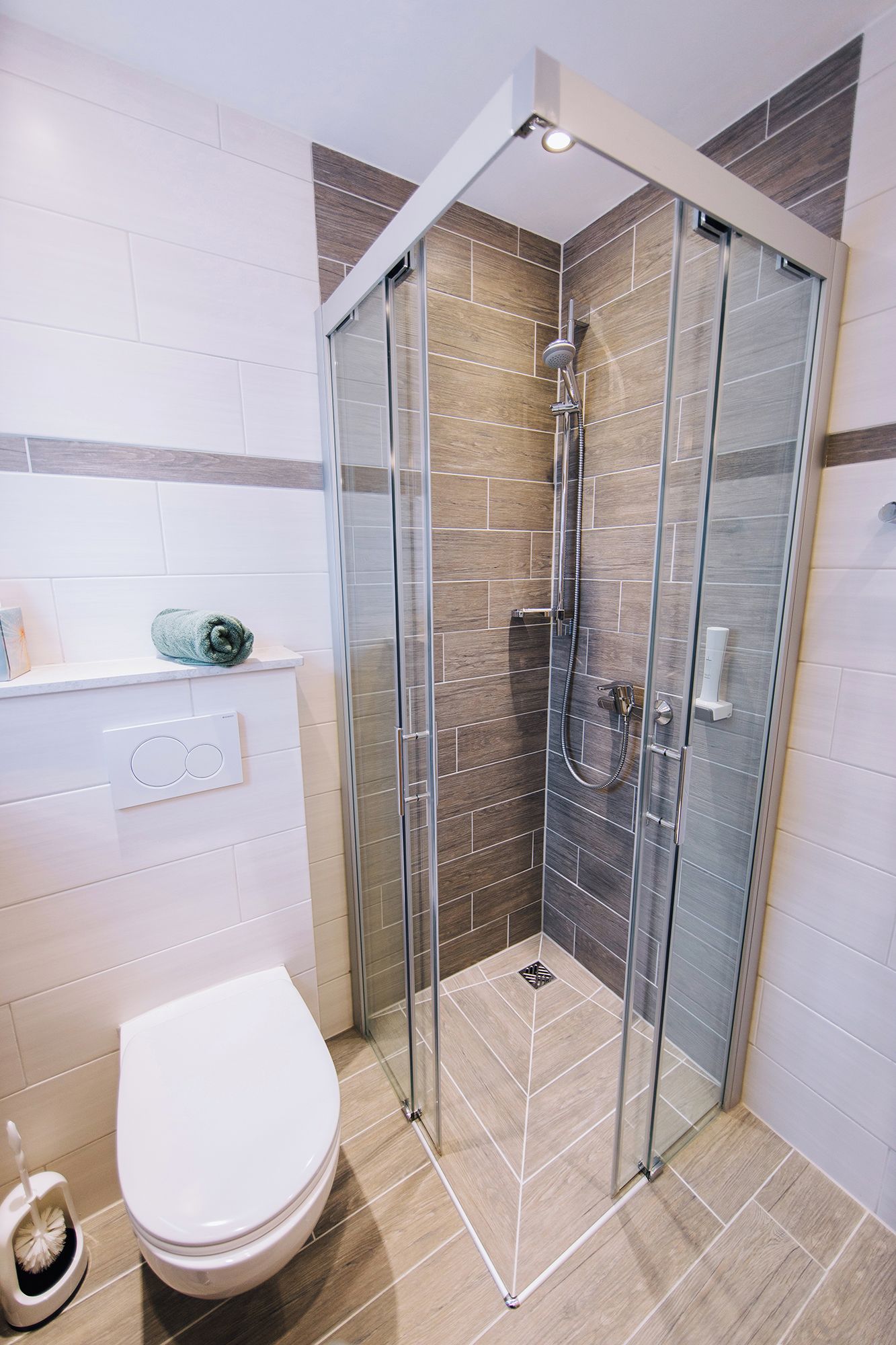 A modern bathroom with a glass-enclosed shower, a toilet, and a towel rack.