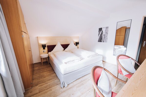 A hotel room with a bed, bedside tables, a mirror, and a chair. - Pension Bavaria (Mittenwald)