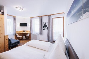 Habitación de hotel con cama, escritorio, silla, televisor y un amplio ventanal.