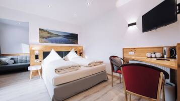 Ein Hotelzimmer mit einem Bett, einem Schreibtisch, einem Sessel, einem Fernseher und einem Bild an der Wand.