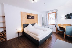 A modern hotel room with a bed, a desk, a chair, and a TV. - Pension Bavaria (Mittenwald)